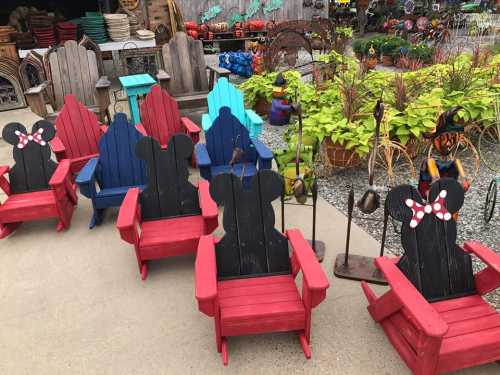 Colorful wooden chairs in red, blue, and black, featuring playful designs, arranged in a vibrant outdoor setting.