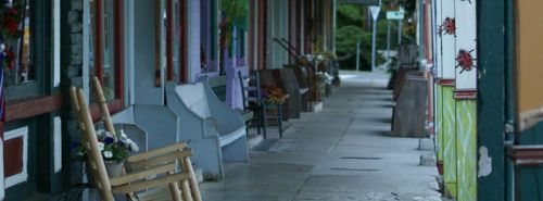 A quiet, colorful street lined with benches and shops, featuring vibrant decorations and a peaceful atmosphere.