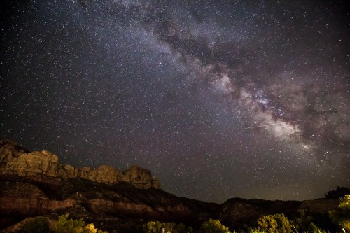 A stunning night sky filled with stars and the Milky Way over rugged mountain silhouettes.