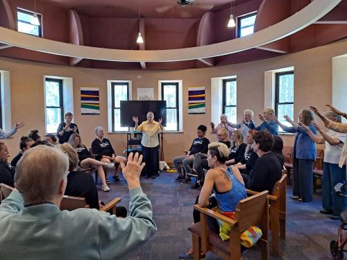 A diverse group of people in a circle, engaged in a lively discussion or activity in a bright, spacious room.