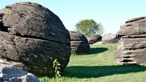 Large, round boulders scattered across a grassy landscape under a clear blue sky.