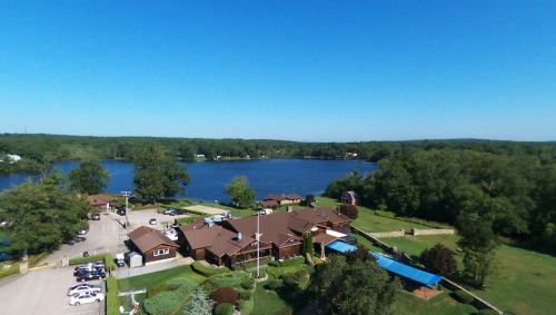 Aerial view of a lakeside property with a brown building, green trees, and a clear blue sky.