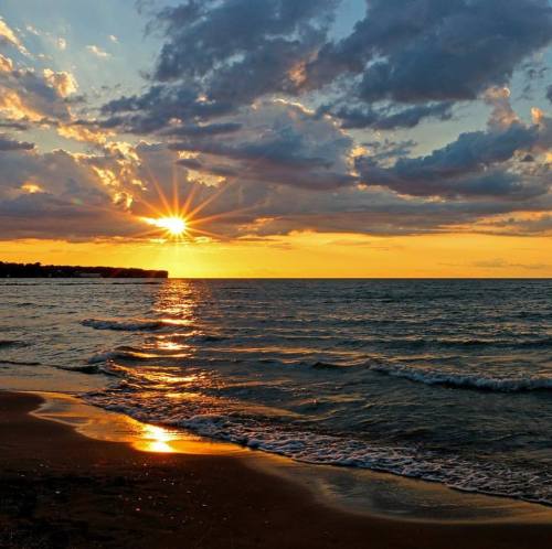A serene sunset over the ocean, with vibrant colors reflecting on the water and clouds scattered in the sky.