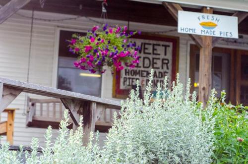 A quaint storefront with a sign for homemade pies, surrounded by flowers and greenery.