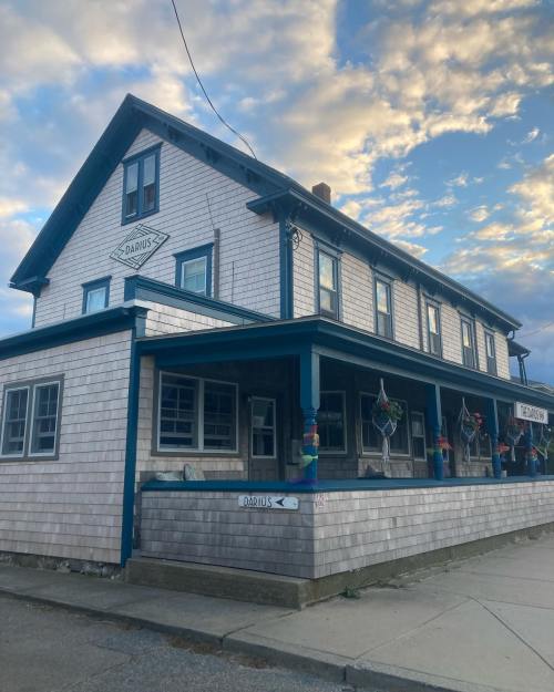A two-story wooden building with a blue trim, featuring colorful decorations and a sign pointing to "Darnus."