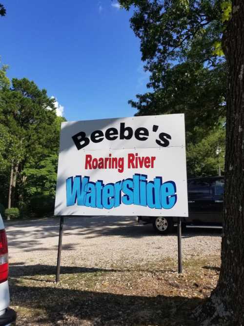 Sign for Beebe's Roaring River Waterslide, surrounded by trees and a clear blue sky.