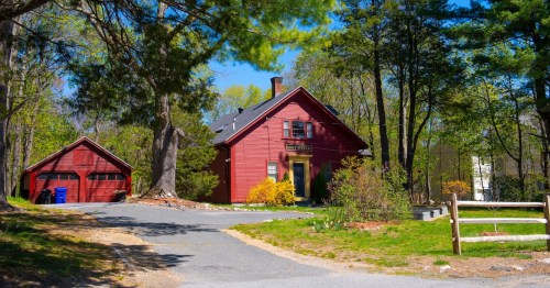 A historic red schoolhouse in Bedford, Massachusetts, among the trees