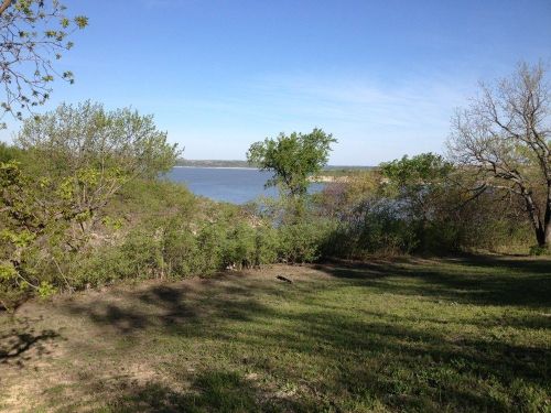 A serene landscape featuring a river surrounded by lush greenery and trees under a clear blue sky.