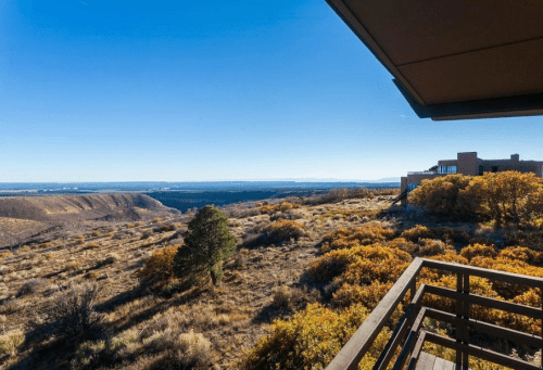 A scenic view from a balcony overlooking a vast landscape with rolling hills and autumn-colored foliage.