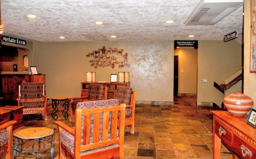 Cozy lobby area with wooden furniture, stone flooring, and decorative wall art. Signs for rooms are visible.