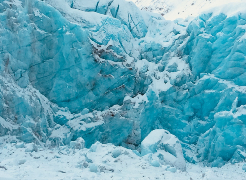 A close-up of a glacier, showcasing vibrant blue ice and snow-covered surfaces.