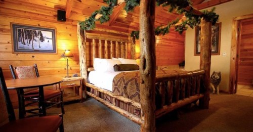 Cozy wooden cabin bedroom with a log bed, rustic decor, and a small dining table.