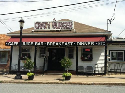 A restaurant named "Crazy Burger" with a sign indicating it serves breakfast and dinner, featuring outdoor seating.