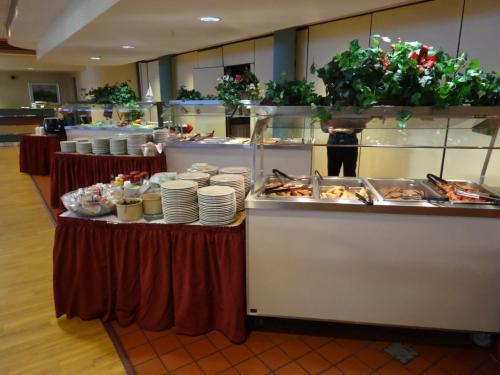 A buffet setup featuring various dishes, plates, and decorative plants on a table with red tablecloths.