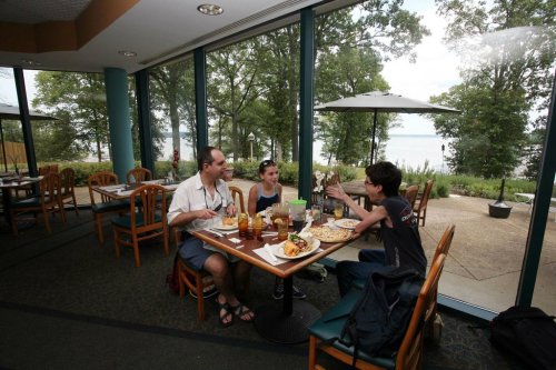 A family enjoys a meal at a restaurant with large windows overlooking a scenic outdoor view.
