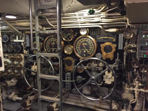 Control panel with dials, levers, and pipes, showcasing vintage machinery in a submarine environment.