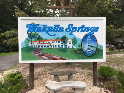 Sign for Wakulla Springs featuring a scenic illustration of the springs and surrounding nature.