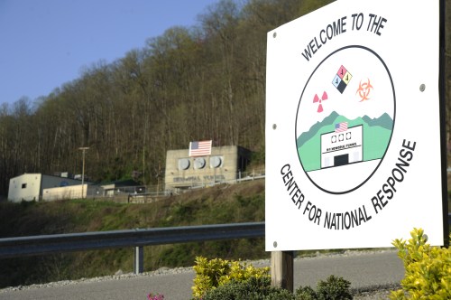 Sign reading "Welcome to the Center for National Response" with a building and hills in the background.