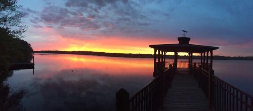 A serene lakeside view at sunset, featuring a gazebo and vibrant colors reflecting on the water.