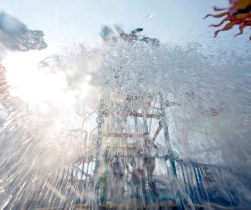 A splash of water from a water slide, with sunlight shining through, creating a fun and vibrant atmosphere.