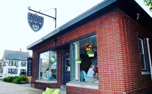A brick building with a sign reading "Norway Brewing Company," featuring large windows and outdoor seating.