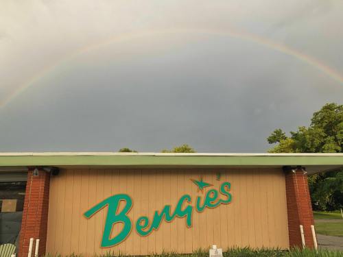 A building with the sign "Bengie's" under a rainbow against a cloudy sky.