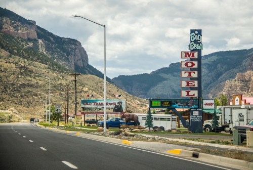 A roadside view featuring the Big Bear Motel sign, mountains in the background, and various advertisements.