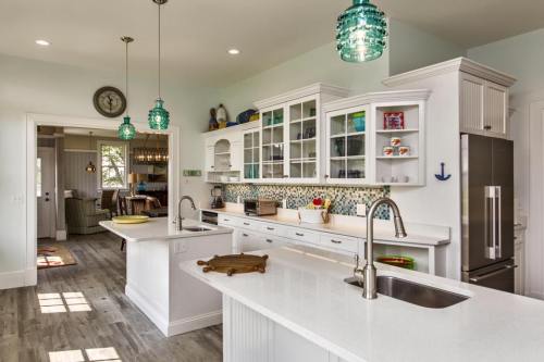 Bright, modern kitchen with white cabinets, turquoise pendant lights, and a spacious island. Open layout to living area.