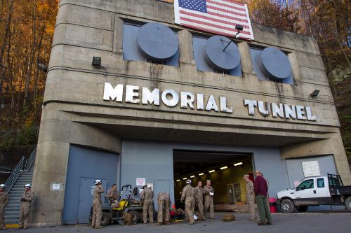 Entrance to Memorial Tunnel with military personnel and equipment, American flag displayed above.