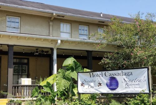 Exterior view of Hotel Cassadaga with a sign for Sandra's Restaurant, surrounded by greenery.