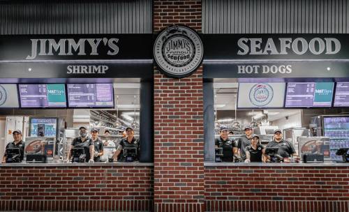A seafood and hot dog stand with staff behind the counter, featuring a sign for "Jimmy's Seafood."