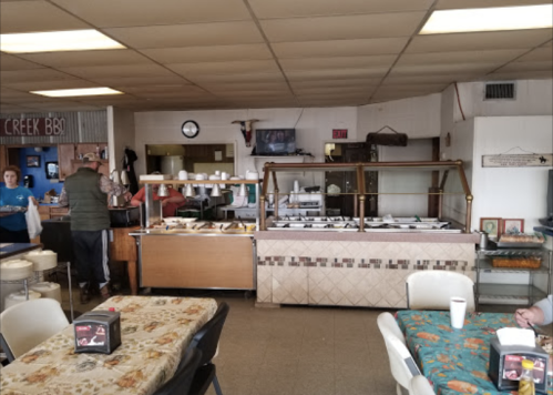 A cozy restaurant interior with a buffet setup, tables, and patrons enjoying their meals.