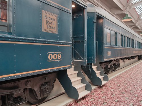 Vintage train cars with blue exteriors and steps, labeled "Nickel Rate Road" and numbered 008 and 009.