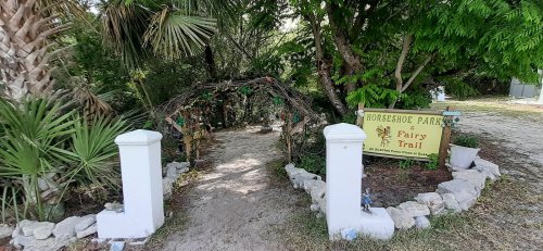 Entrance to a whimsical fairy trail at Horseshoe Park, framed by greenery and a sign welcoming visitors.