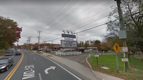 A street view of a McDonald's and a marquee sign along a road, with cloudy skies and autumn foliage.