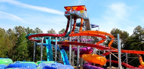 A colorful water slide structure with multiple twisting slides and a tower, surrounded by inflatable tubes.