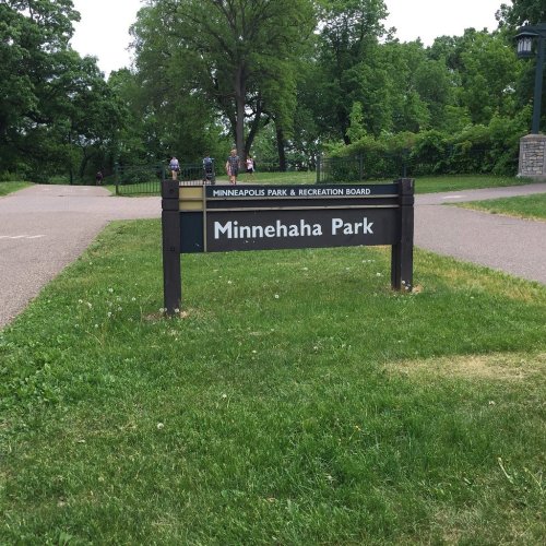 Sign for Minnehaha Park in a green park setting, with trees and a pathway visible in the background.