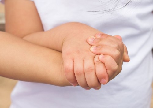 Two children's hands clasped together, symbolizing friendship and connection.