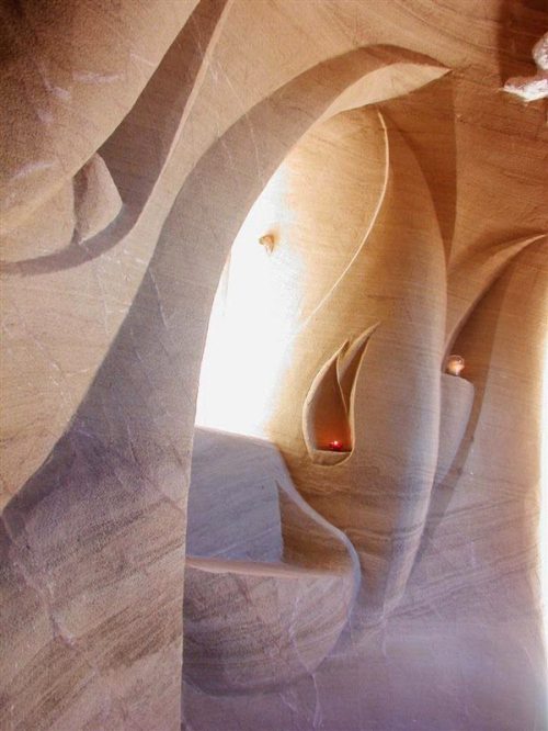 Intricate sandstone formations with soft curves and natural light illuminating the textured surfaces.