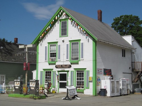 A colorful, two-story building with green trim and decorative lights, featuring vintage gas pumps outside.