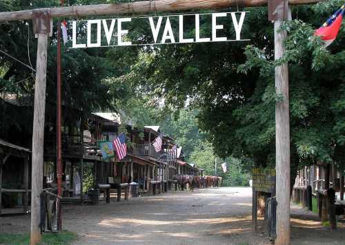 A wooden archway reading "Love Valley" leads into a rustic street lined with buildings and flags.