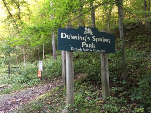 Sign for Dunning's Spring Park, surrounded by trees and greenery, indicating Decorah Parks & Recreation.