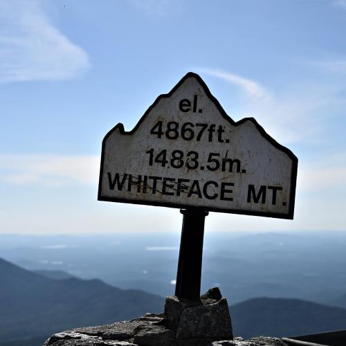 Sign marking the elevation of Whiteface Mountain at 4867 feet, with a scenic view of the surrounding landscape.