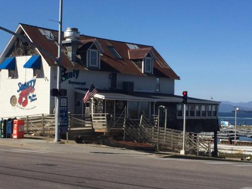 A seaside restaurant with a weathered exterior, blue awnings, and an American flag, near a traffic light.
