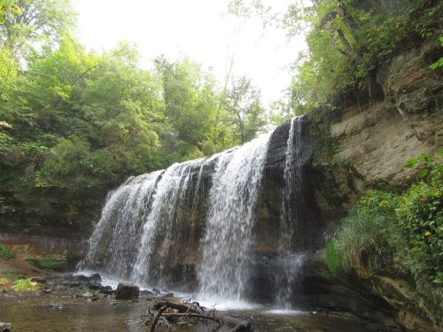 A serene waterfall cascading over rocky cliffs, surrounded by lush green trees and foliage.
