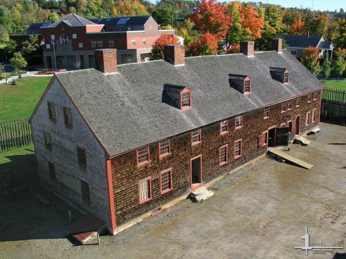 Historic building with a wooden exterior, surrounded by trees with autumn foliage and a clear blue sky.