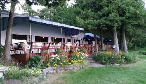 A cozy restaurant with outdoor seating surrounded by greenery and colorful flowers.