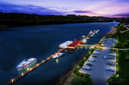 A serene river scene at dusk, featuring boats docked at a pier and a parking lot along the water's edge.