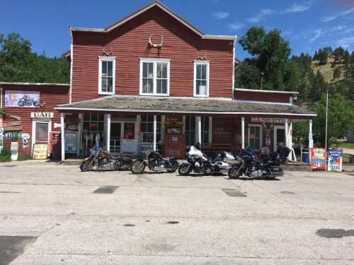 A row of motorcycles parked in front of a red historic building on a sunny day.