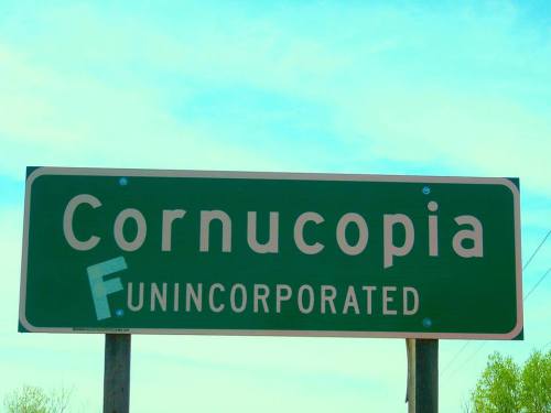 Sign reading "Cornucopia" with the word "Funincorporated" partially obscured, set against a blue sky.